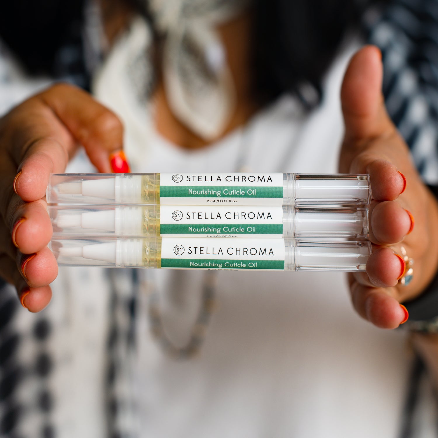 woman holding three cuticle oils pens in her outstretched hands