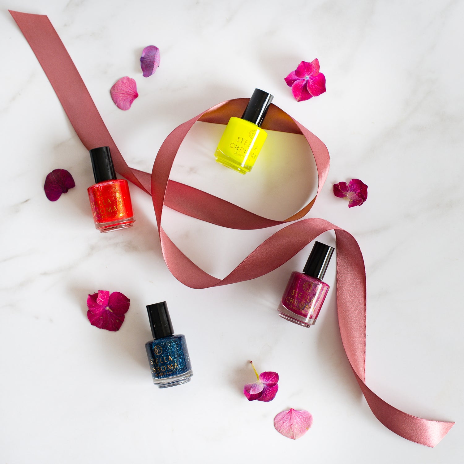 4 nails polishes and a ribbon on a marble top